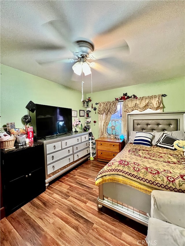 bedroom featuring a textured ceiling, wood-type flooring, and ceiling fan