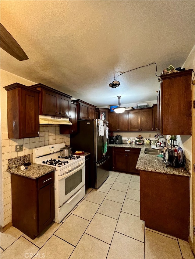 kitchen with sink, a textured ceiling, white gas range oven, dark stone countertops, and decorative backsplash