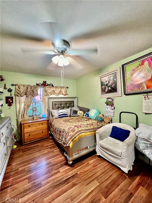 bedroom featuring ceiling fan, hardwood / wood-style floors, and a textured ceiling