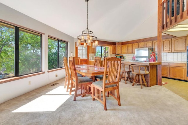 dining room featuring light colored carpet, a wealth of natural light, and an inviting chandelier