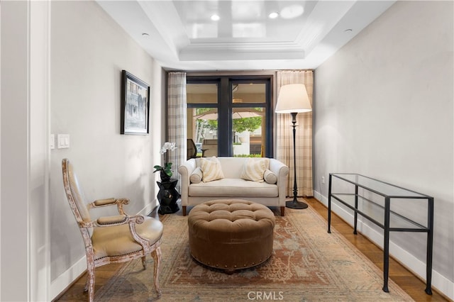 sitting room with a tray ceiling and hardwood / wood-style flooring