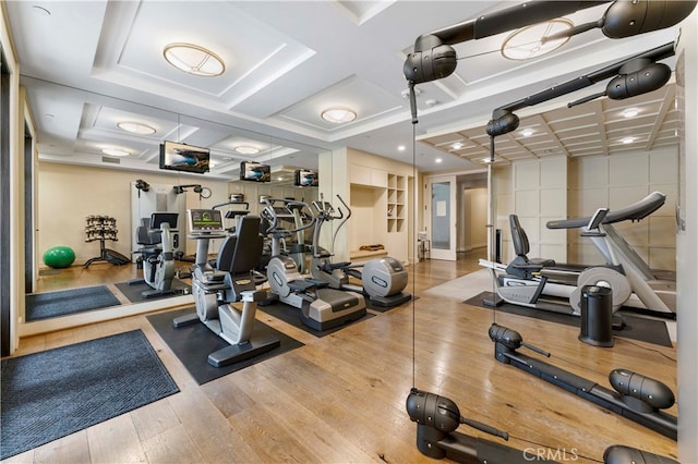 exercise room with coffered ceiling and light hardwood / wood-style flooring