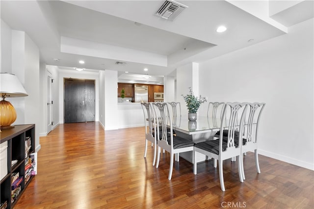 dining space with a tray ceiling and hardwood / wood-style flooring