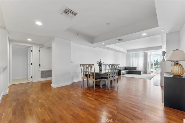 dining space featuring a raised ceiling and hardwood / wood-style floors