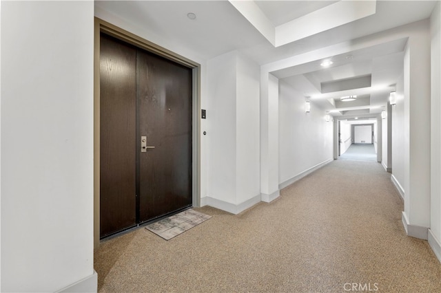 hall featuring light carpet and a raised ceiling