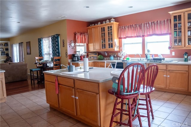 kitchen with a breakfast bar, light tile patterned flooring, a kitchen island with sink, and sink