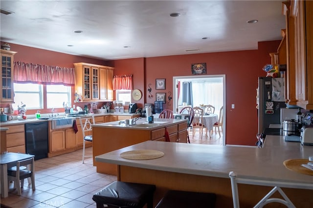 kitchen featuring stainless steel fridge, light tile patterned floors, sink, a kitchen island with sink, and black dishwasher