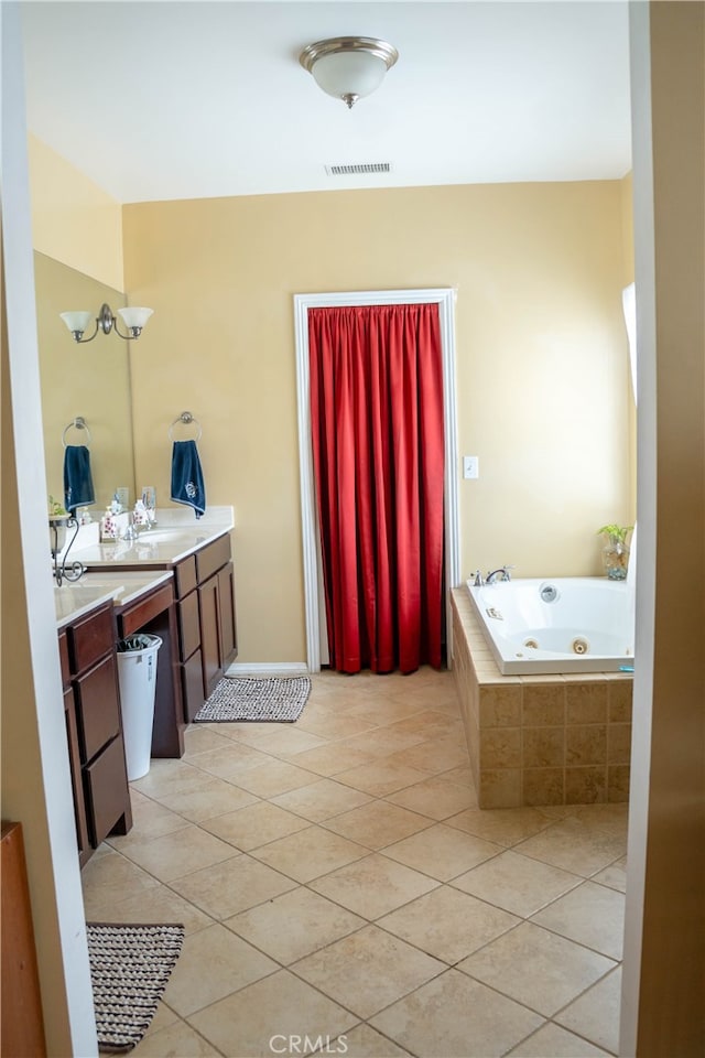 bathroom featuring tiled tub, vanity, and tile patterned floors