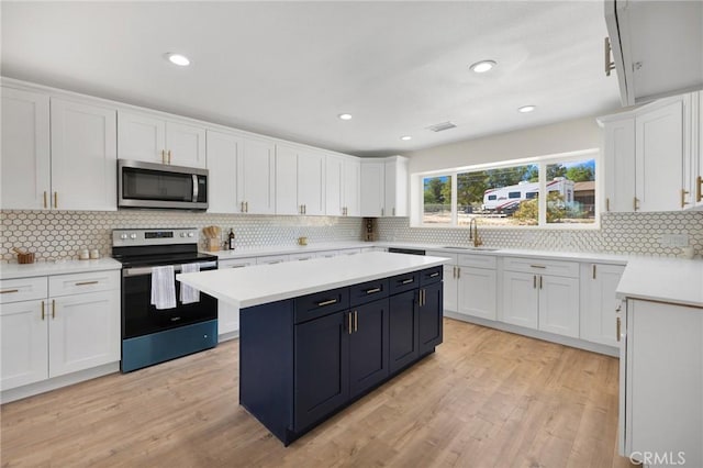 kitchen featuring tasteful backsplash, light hardwood / wood-style flooring, white cabinets, and stainless steel appliances