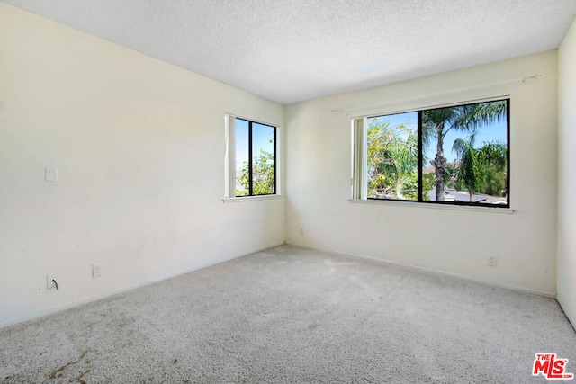 carpeted empty room with a textured ceiling