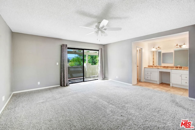 unfurnished bedroom with access to exterior, a textured ceiling, built in desk, and ceiling fan