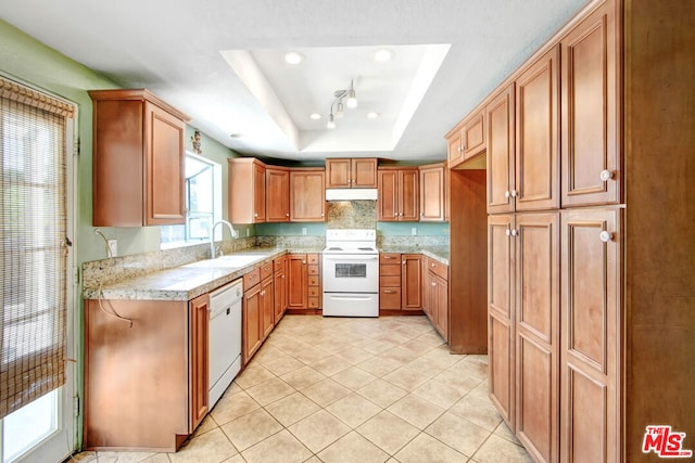 kitchen with white appliances, sink, light tile patterned floors, and a tray ceiling