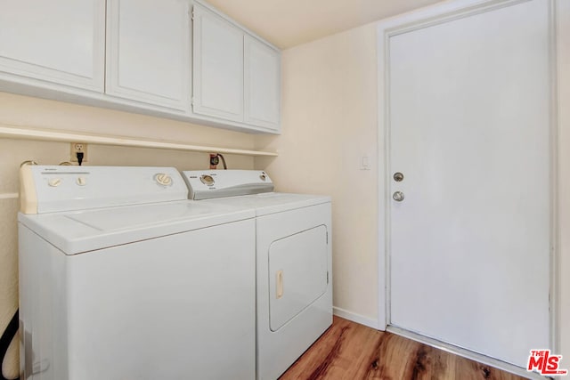 clothes washing area with washer and dryer, light hardwood / wood-style flooring, and cabinets