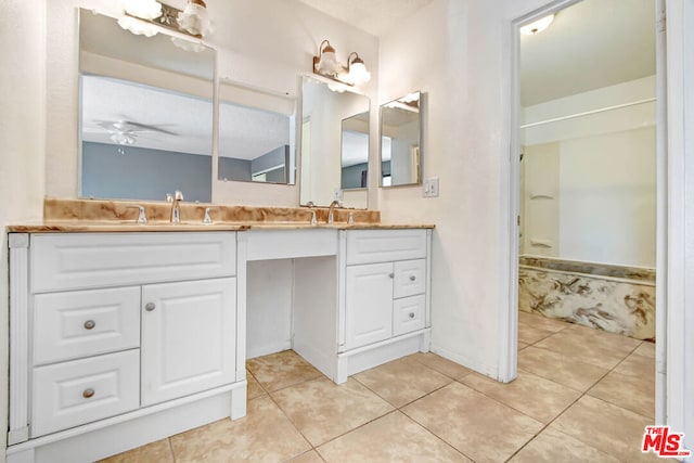 bathroom featuring tile patterned flooring, ceiling fan, a relaxing tiled tub, and vanity