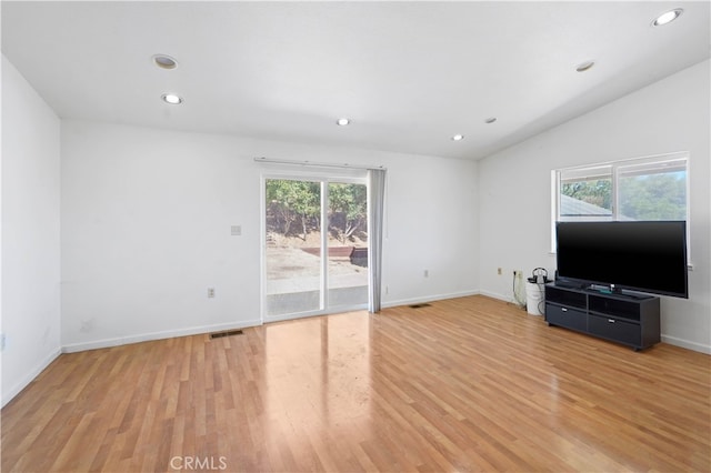 unfurnished living room with light hardwood / wood-style flooring, plenty of natural light, and vaulted ceiling