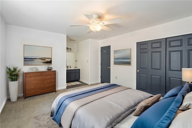 bedroom with connected bathroom, light carpet, ceiling fan, and a closet