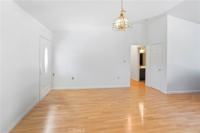 empty room featuring light wood-type flooring and a chandelier