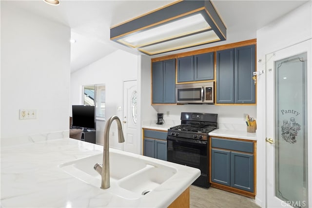 kitchen with blue cabinets, sink, vaulted ceiling, and black gas range oven