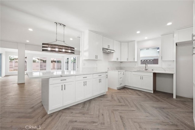 kitchen featuring kitchen peninsula, white cabinetry, sink, and light parquet floors