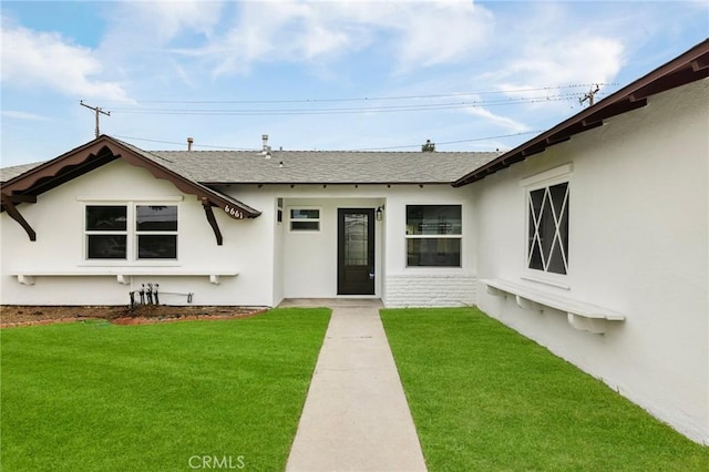 view of exterior entry featuring a lawn