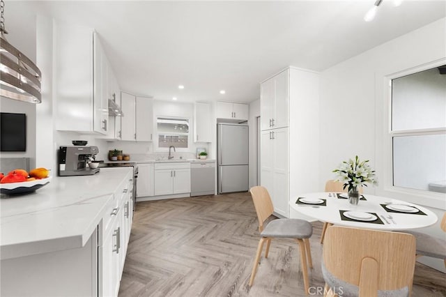 kitchen with dishwasher, sink, fridge, light stone counters, and white cabinetry