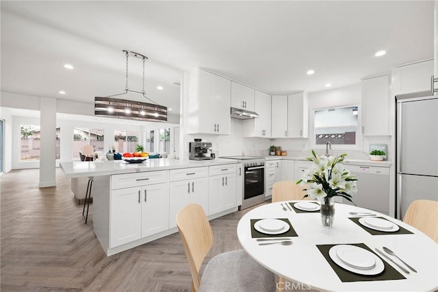 kitchen featuring pendant lighting, white cabinetry, appliances with stainless steel finishes, and light parquet flooring