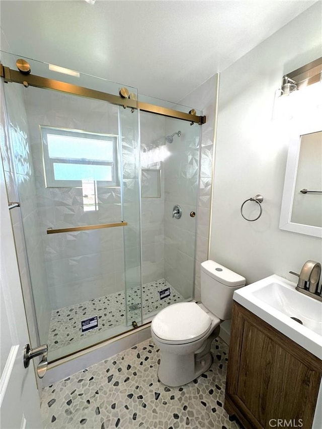 bathroom with tile patterned flooring, vanity, toilet, and a shower with shower door