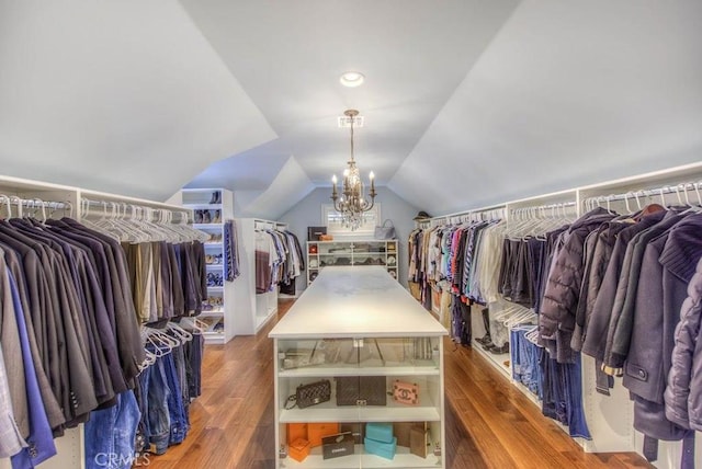 spacious closet with wood-type flooring, vaulted ceiling, and a notable chandelier