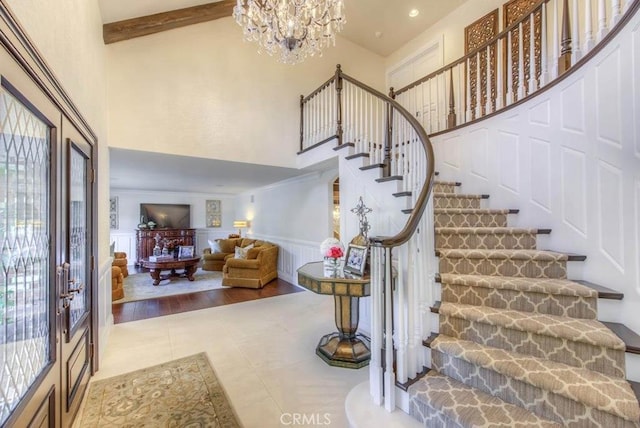 tiled foyer featuring a healthy amount of sunlight, french doors, an inviting chandelier, and a high ceiling