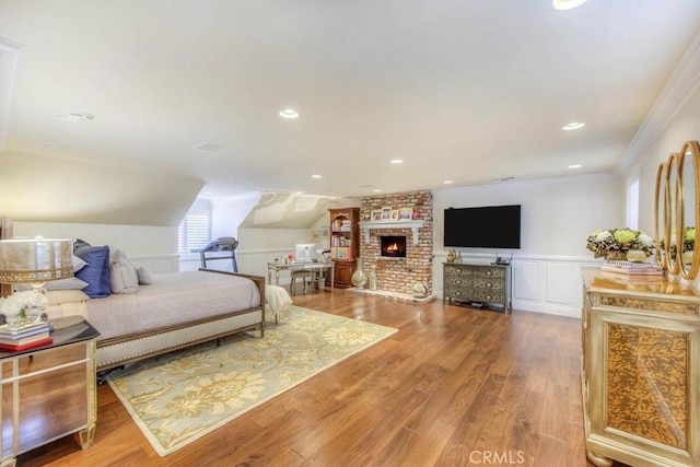 bedroom featuring a brick fireplace, hardwood / wood-style floors, and crown molding