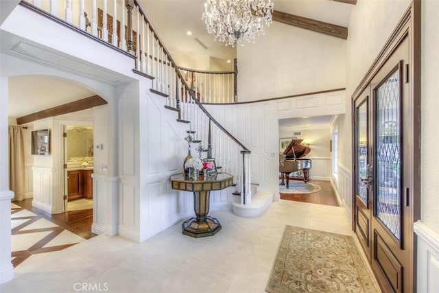 tiled entrance foyer featuring a high ceiling and a notable chandelier