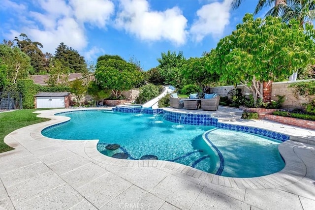 view of swimming pool featuring a shed, a patio area, and a water slide