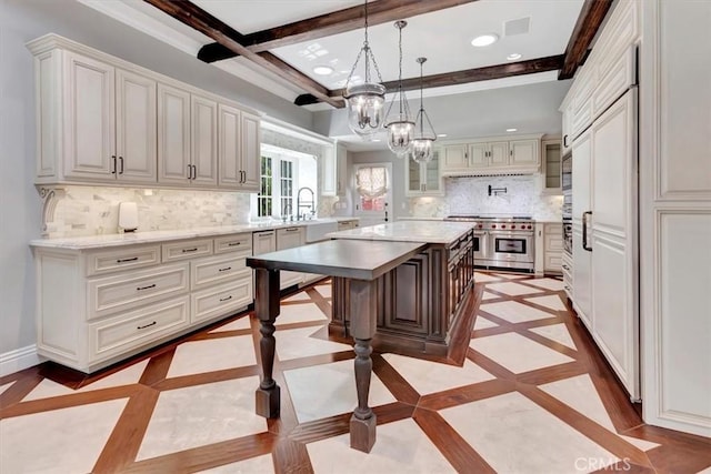 kitchen featuring range with two ovens, a breakfast bar, a kitchen island, white cabinets, and decorative light fixtures