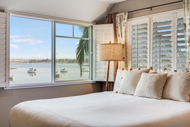 bedroom with a water view and vaulted ceiling