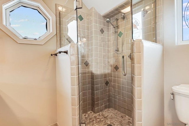 bathroom featuring toilet and a shower with shower door