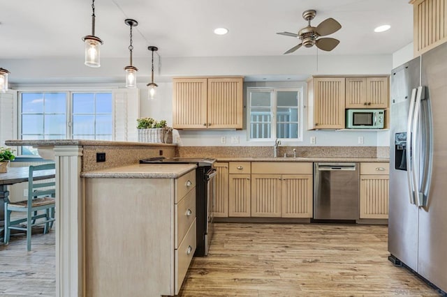 kitchen featuring sink, light brown cabinets, light hardwood / wood-style flooring, decorative light fixtures, and appliances with stainless steel finishes