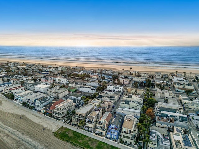 aerial view at dusk featuring a water view and a view of the beach