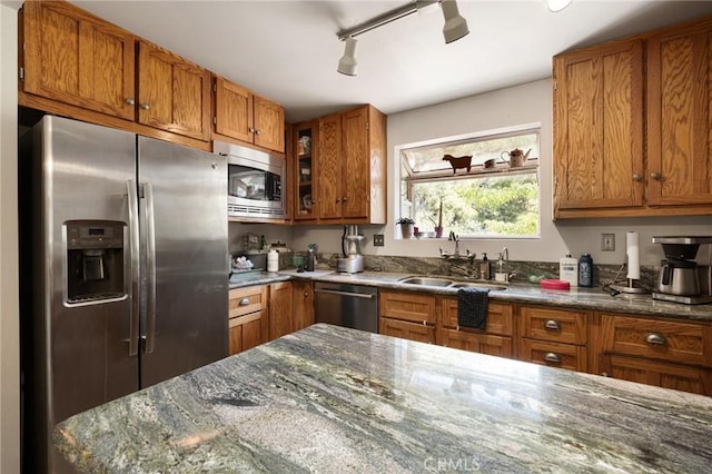 kitchen with dark stone countertops, sink, rail lighting, and appliances with stainless steel finishes