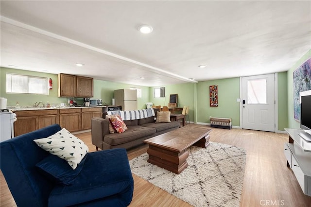 living room with light hardwood / wood-style flooring, plenty of natural light, and sink