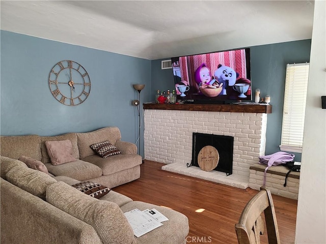 living room featuring wood-type flooring and a brick fireplace