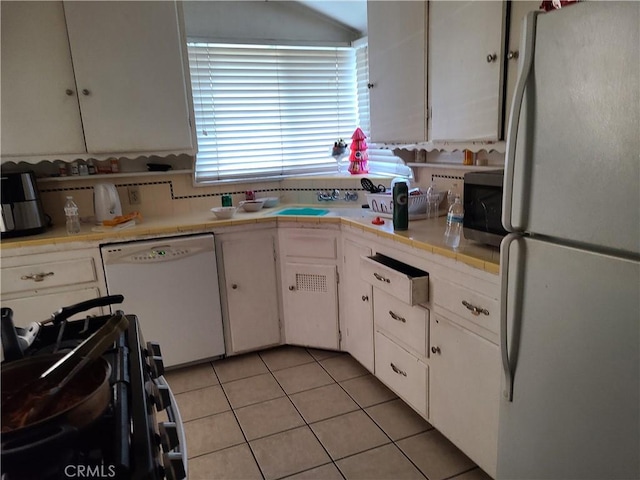 kitchen featuring white cabinetry, light tile patterned floors, and white appliances