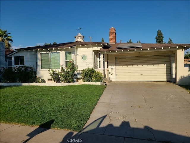 view of front of house featuring solar panels, a garage, and a front lawn