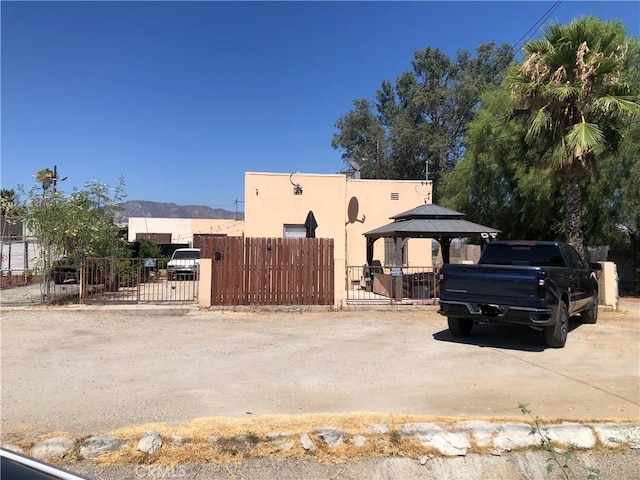 view of front of house featuring stucco siding, a gate, a gazebo, and fence
