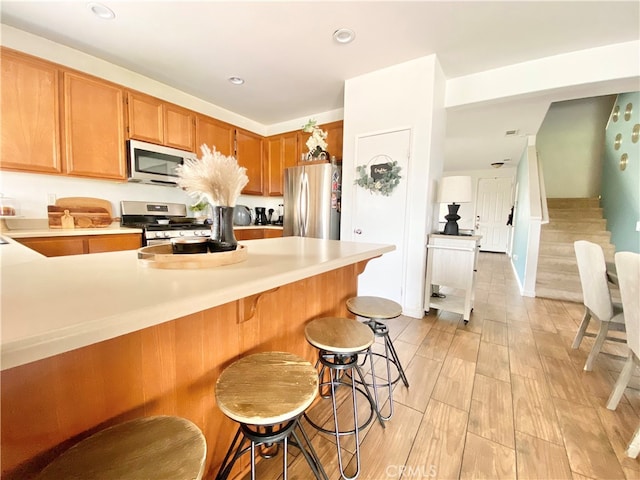 kitchen featuring light hardwood / wood-style flooring, stainless steel appliances, and a breakfast bar