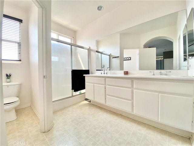 bathroom with walk in shower, vanity, and toilet