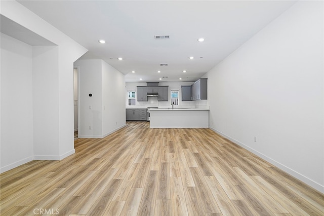 unfurnished living room with light hardwood / wood-style floors and sink