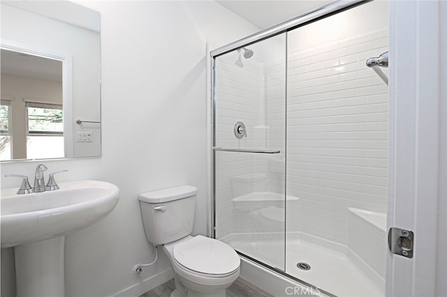 bathroom with sink, a shower with door, and toilet