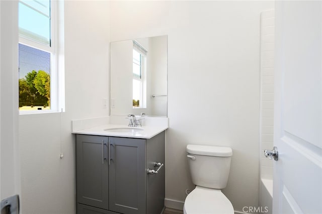 bathroom featuring a bath, vanity, toilet, and a wealth of natural light