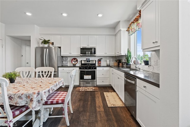 kitchen with stainless steel appliances, white cabinetry, and dark wood-type flooring