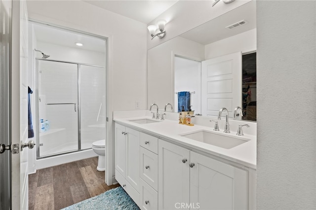 bathroom with hardwood / wood-style floors, vanity, a shower with shower door, and toilet